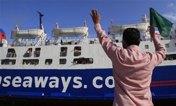 In this photo taken on a government-organized tour, a Libyan man waves a iconic green-colored flag as he greets a ship after a 27-hour boat ride from the rebel-held east in a port in Tripoli, Libya, on June 26. The ship docked Sunday morning in Tripoli's main port, carrying mostly families and elderly traveling from Benghazi. On Friday, the Red Cross brought about 300 people to Benghazi from Tripoli who had wanted to go to the east.
